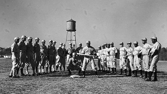 The service teams, though segregated (like the wartime U.S.armed forces) also featured African-American teams and the Marines were no different. This team from Montford Point (at Camp Lejune, NC) featured a star of the Negro Leagues (Dan Bankhead) who would go on to be the first pitcher in the major leagues, playing for the Brooklyn Dodgers. Note the two squads of players – those on the left are wearing the road gray and the players on the right are in white.