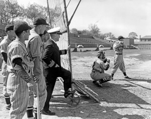 Harold "Pee Wee" Reese takes a swing at the plate for the Norfolk Training Station's Blue Jackets team. (Former) New York Yankees' shortstop Phil Rizzuto (nearest at left) watches with his Bluejackets teammates.